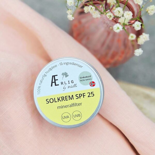 solkrem fra ærlig by walle ligger på lys rosa tekstil